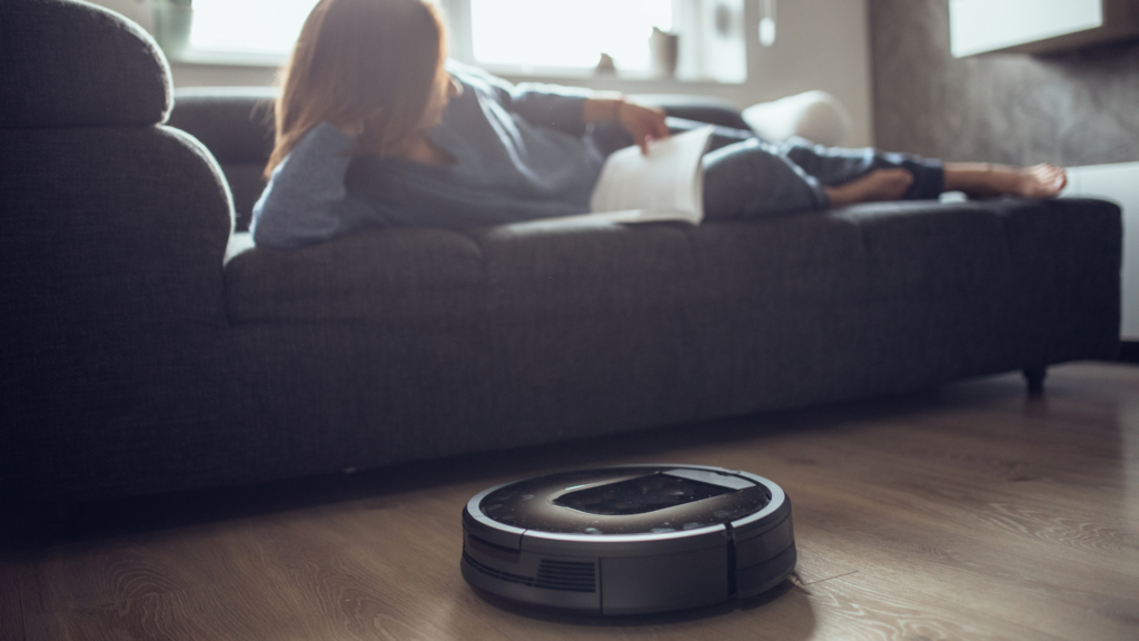 Robot vacuum cleaning floor while woman is on the couch reading a book
